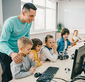 teacher helping students at computers
